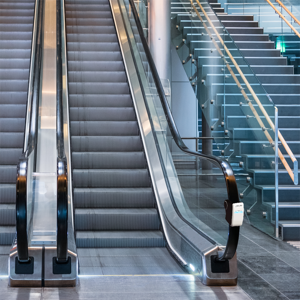 An Escalator with the crocus exterior handrail disinfection unit on one side of the escalators handrail