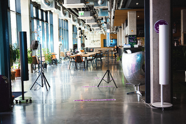 Conceptual application image of UV Can Sanitize's HEATHER UV-C disinfection Corn Light in a restaurant on a black stand with UV-C light on.