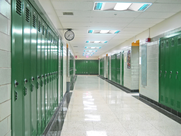 Conceptual application image of 7 of UV Can Sanitize's GALAX Surface-02 UV-C Disinfection Panel lights installed the ceiling of a school hallway.